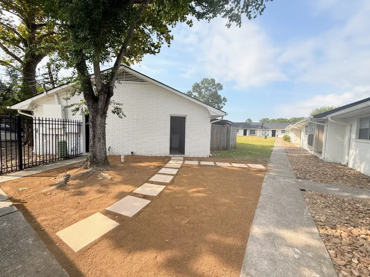 Landscaped walkway between two townhome buildings at Luna Bay, with stepping stones and a shade tree.